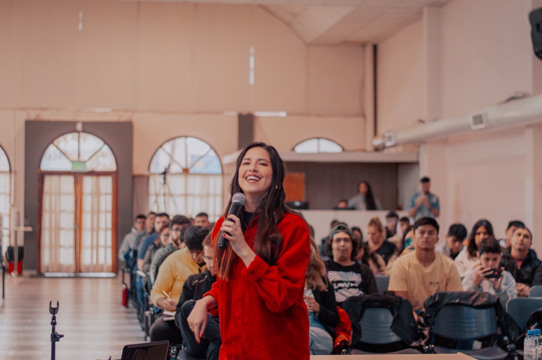 a-woman-standing-in-front-of-a-crowd-holding-a-microphone-nk02shlfwdm